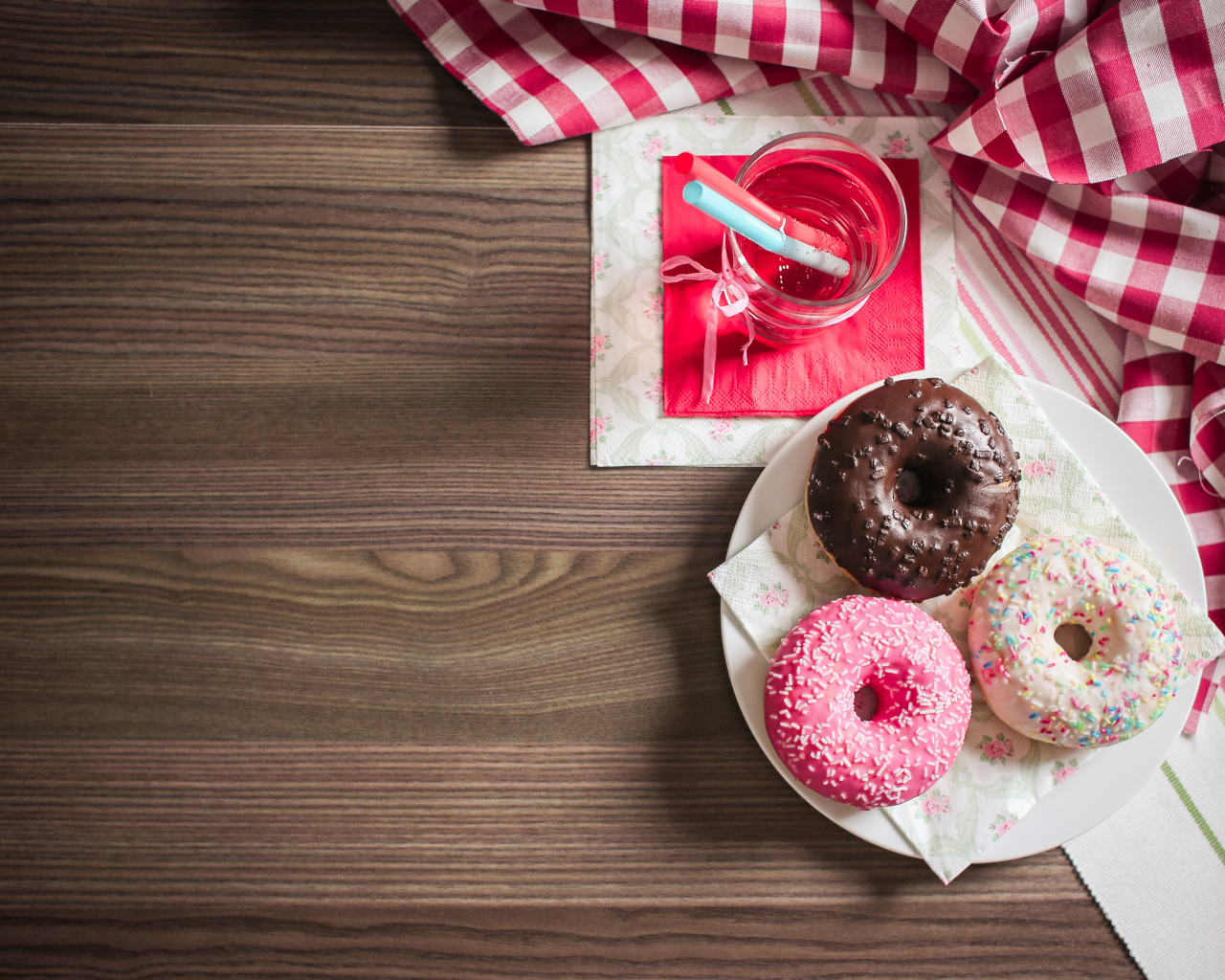 Три сладких пончика с глазурью на столе с лимонадом