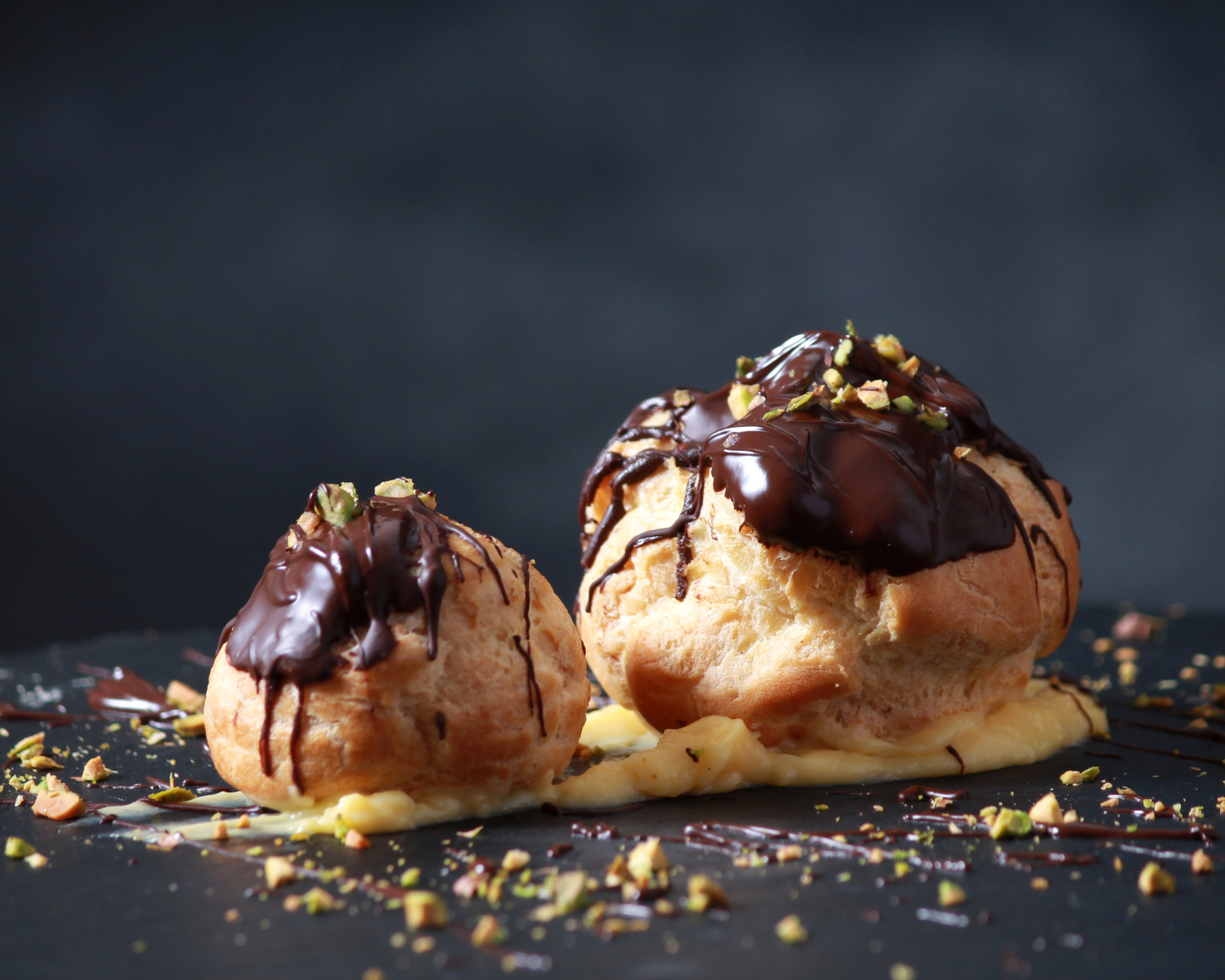 Два заварных пирожных с шоколадом на сером фоне