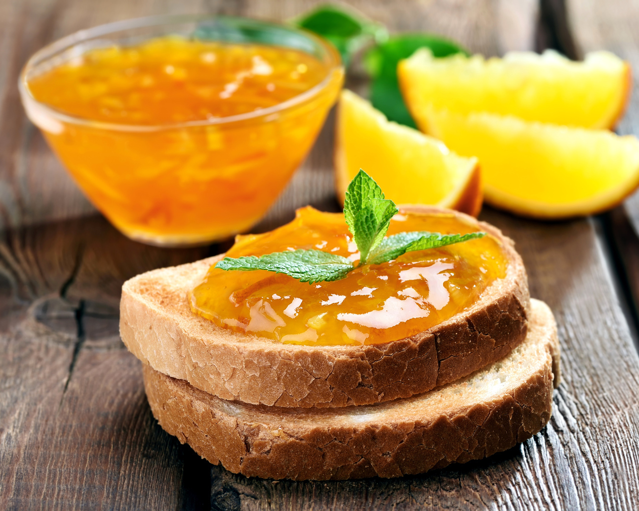 Два кусочка хлеба с апельсиновым джемом на столе с мятой