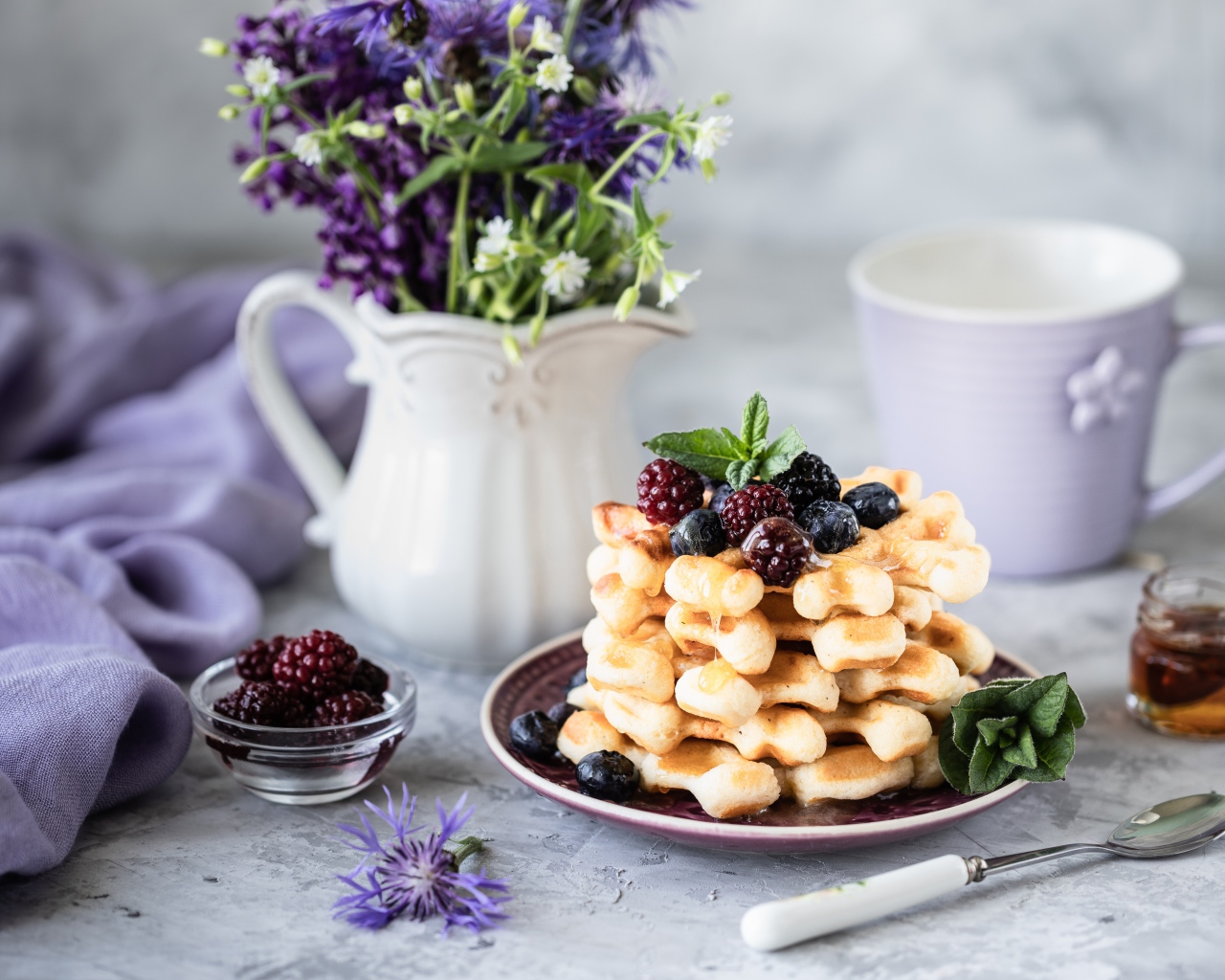Вафли с ягодами черники и ежевики на столе с букетом