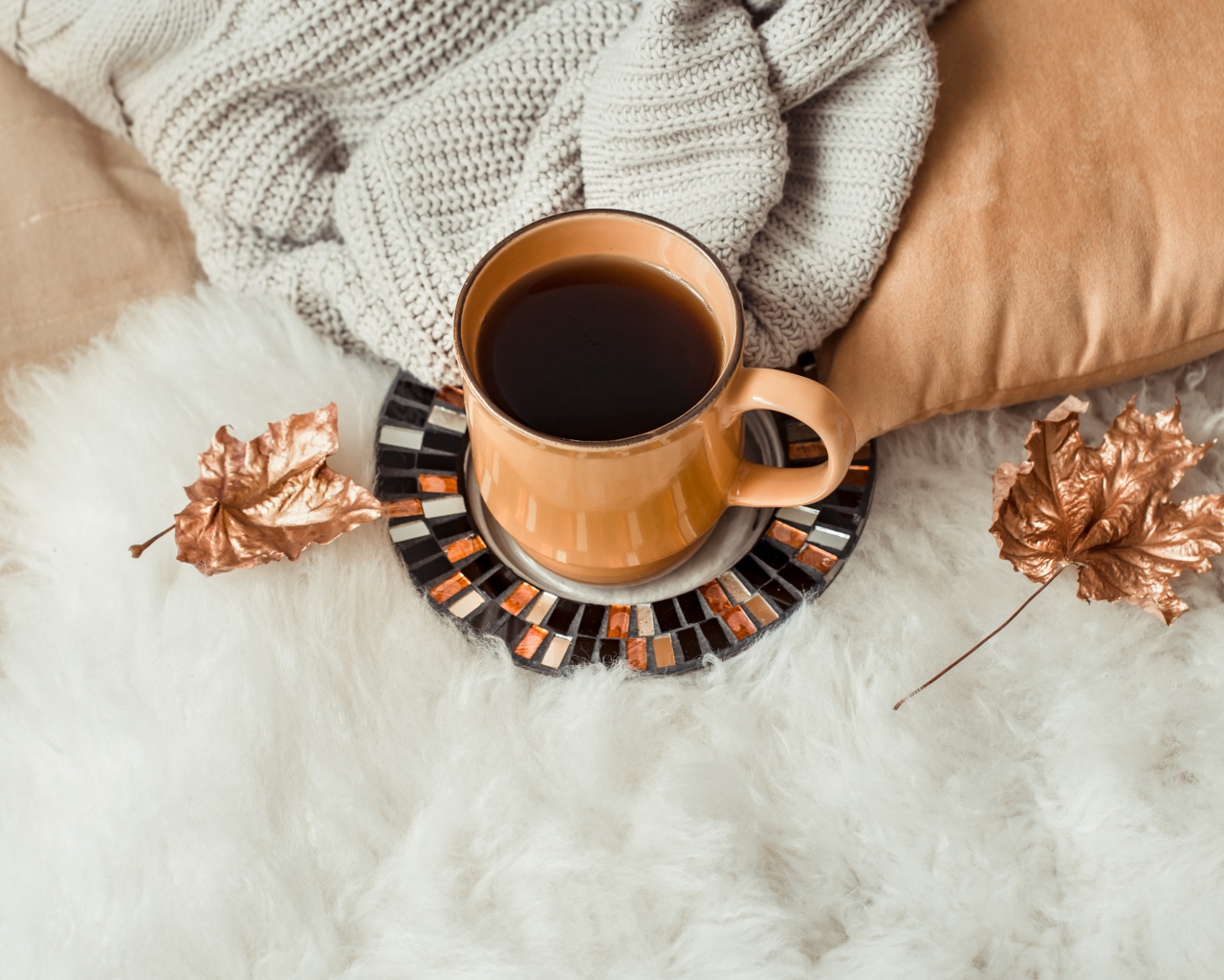 Чашка кофе стоит на покрывале с теплым свитером 