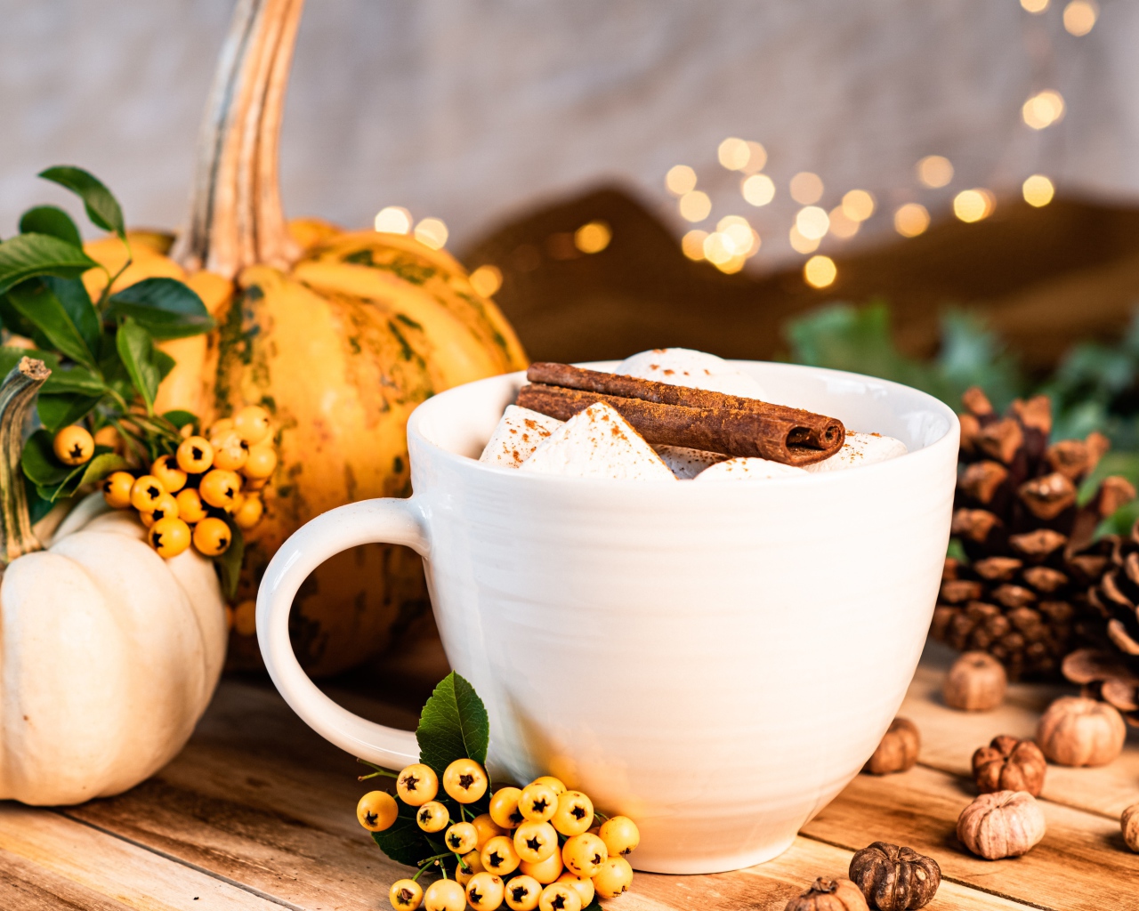 Чашка горячего маршмеллоу с корицей на столе с тыквой и шишками
