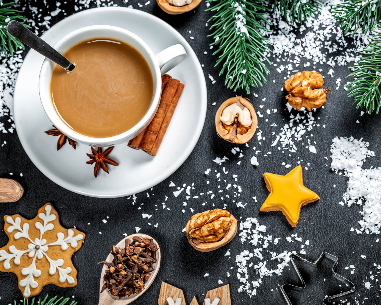 Чашка горячего кофе на столе с орехами и еловыми ветками 