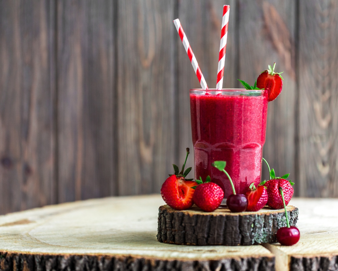 Стакан ягодного смузи на столе с клубникой и вишней