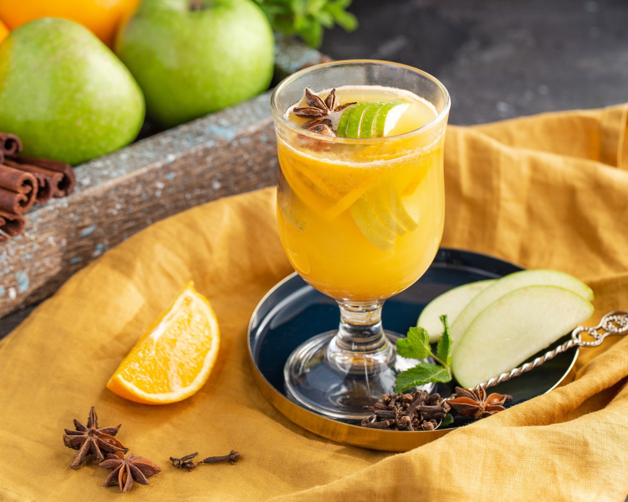 Стакан лимонада на столе с яблоками и корицей 