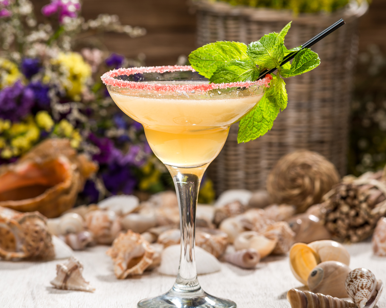 Коктейль с мятой в бокале на столе с ракушками 