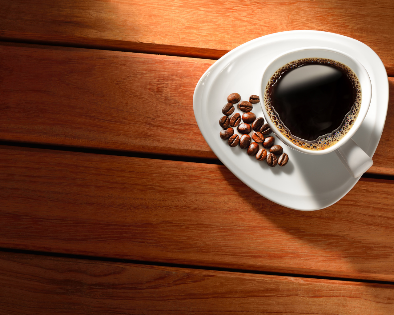 Чашка кофе на тарелке с зернами на деревянном столе