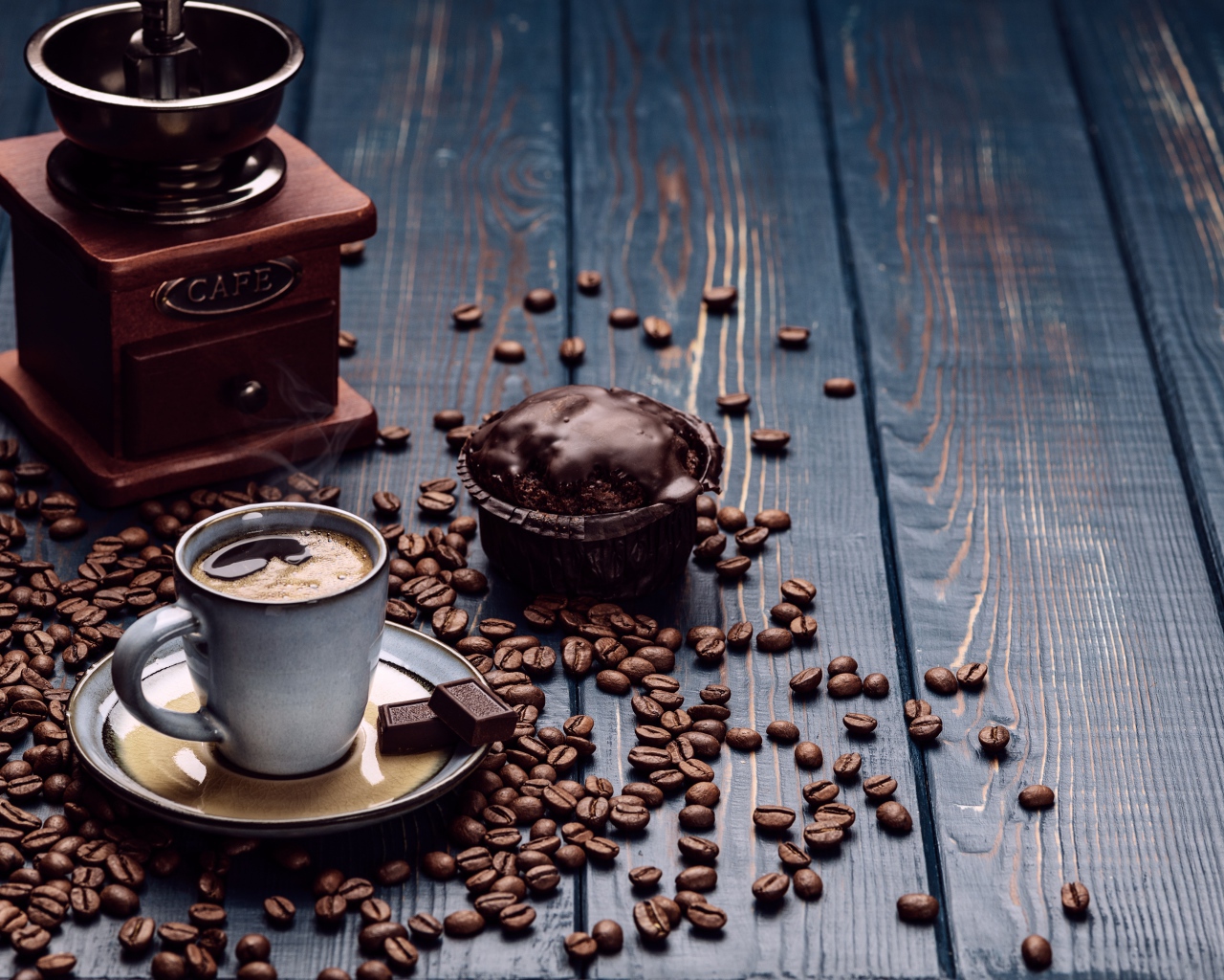 Чашка кофе на столе с шоколадным кексом и кофемолкой