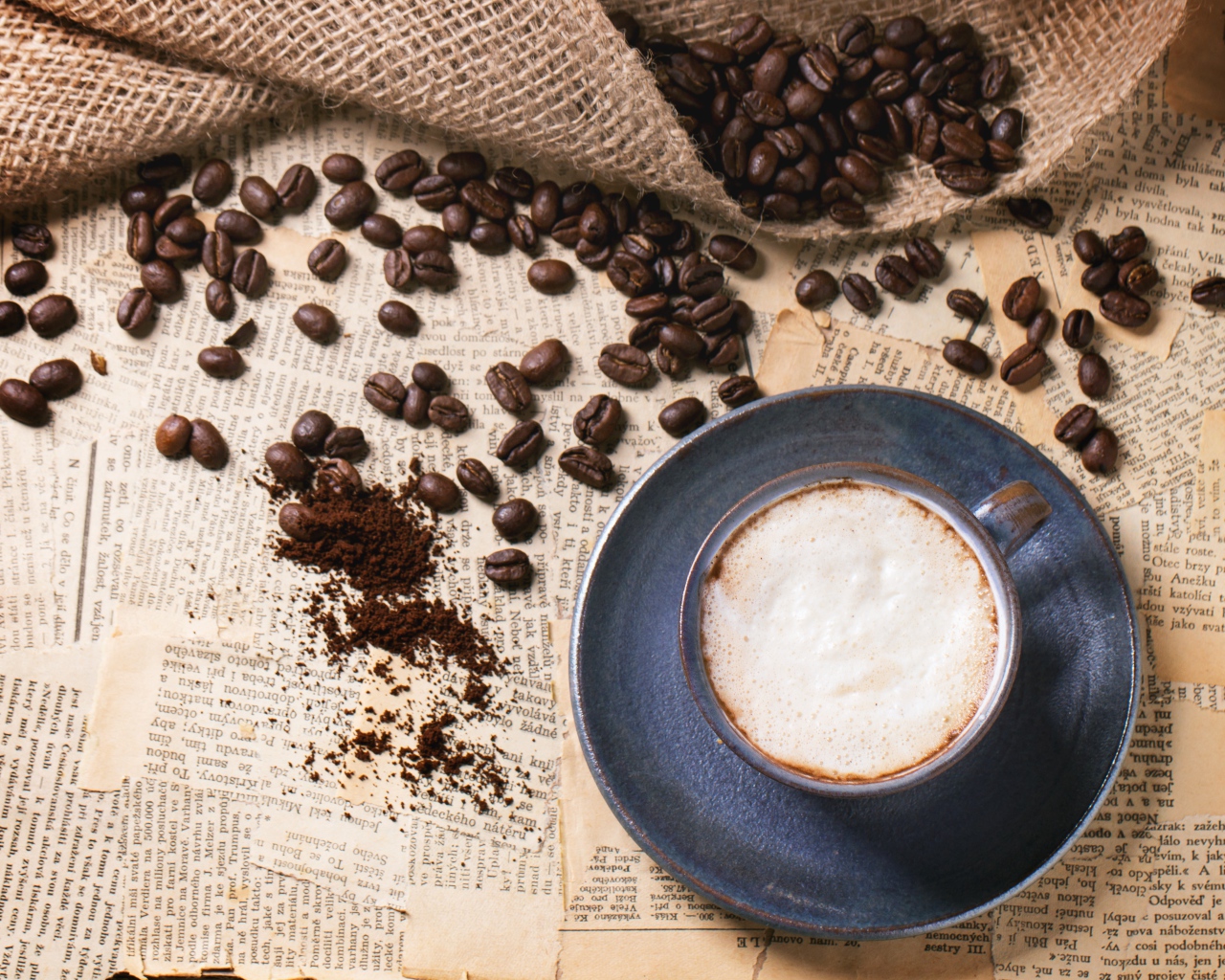 Чашка кофе на столе со старыми газетами и зернами