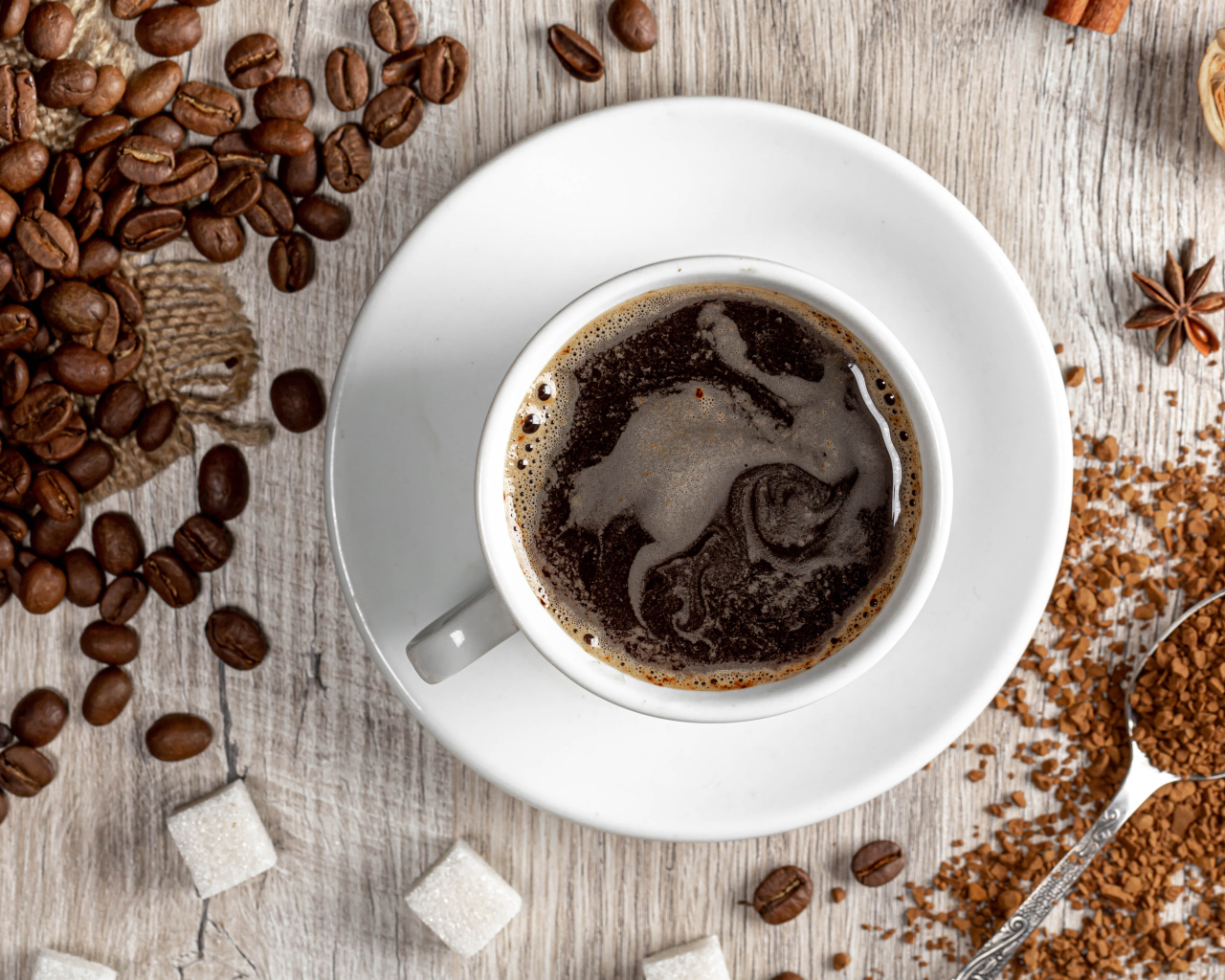 Чашка кофе на столе с сахаром и кофейными зернами