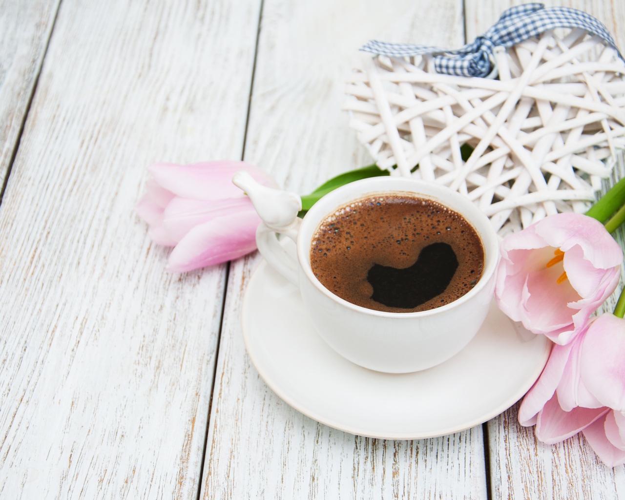 Чашка кофе на столе с розовыми тюльпанами и плетеным сердцем