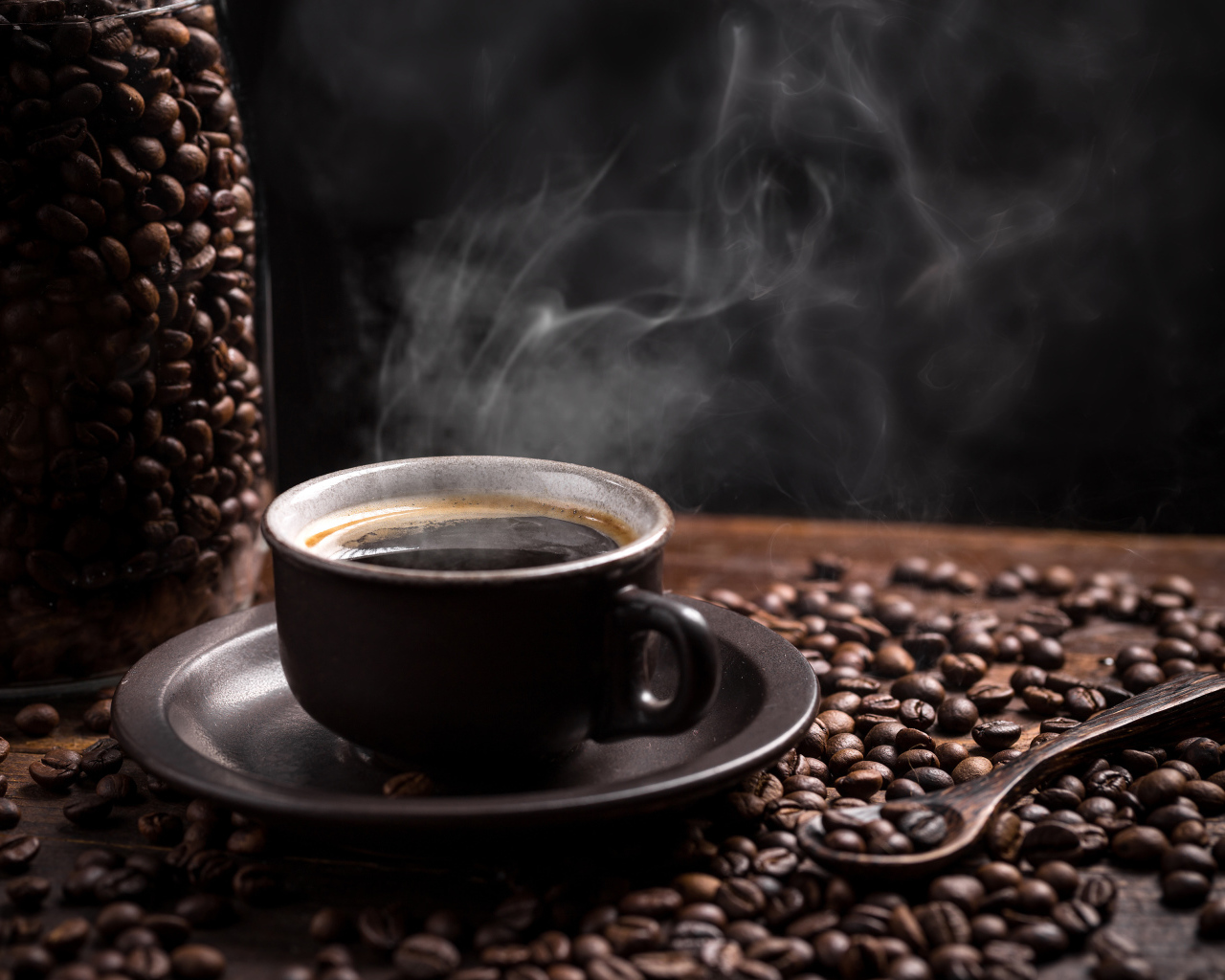 Чашка горячего ароматного кофе на столе с зернами и ложкой