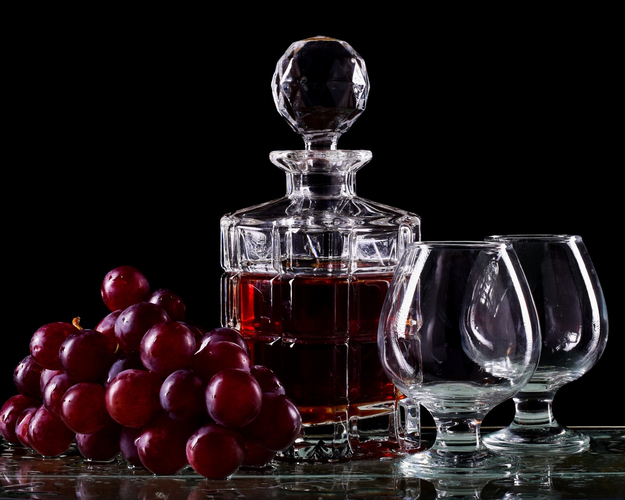Графин с коньяком на столе с бокалами и виноградом