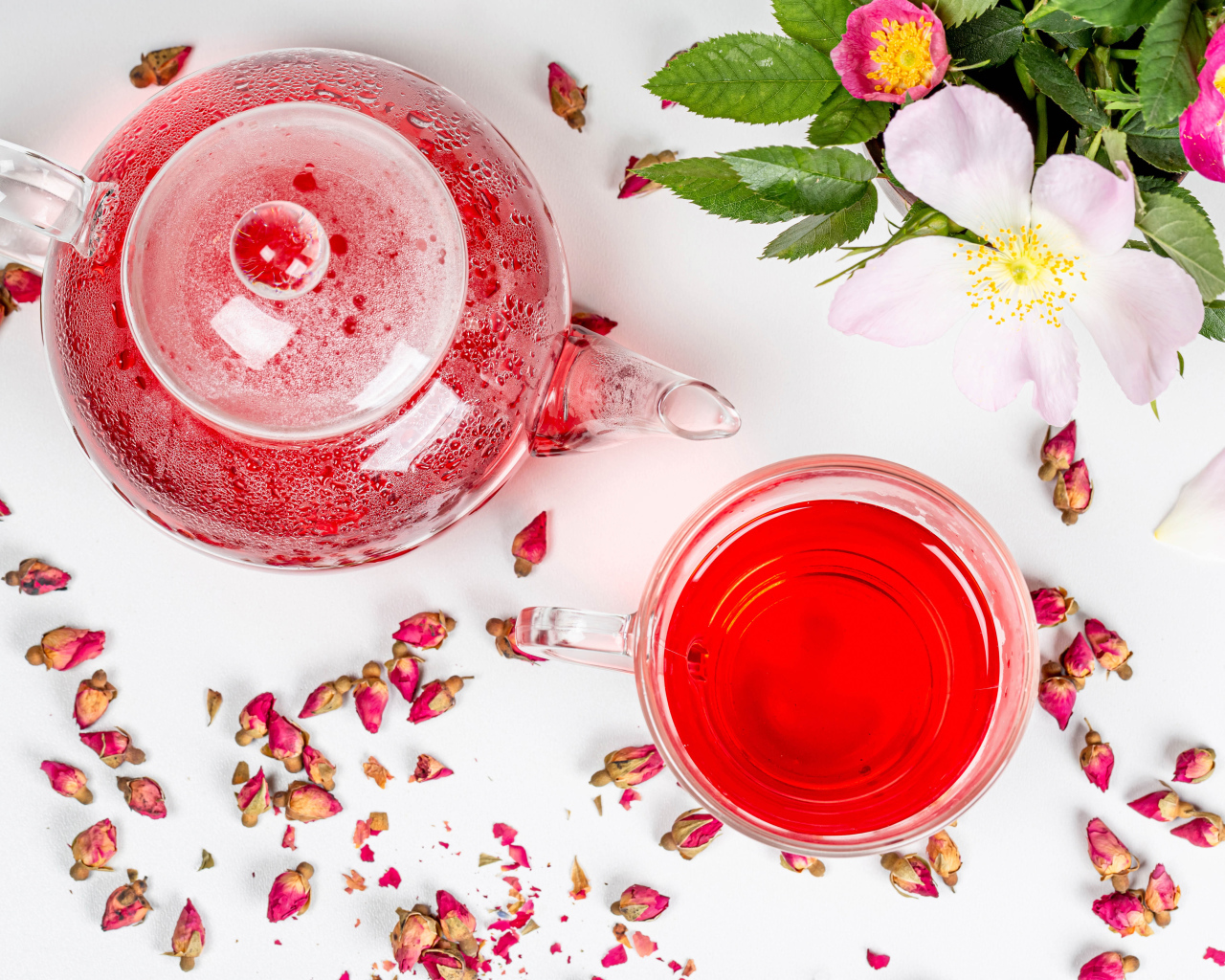 Свежий чай с шиповника в стеклянной чашке на столе с чайником