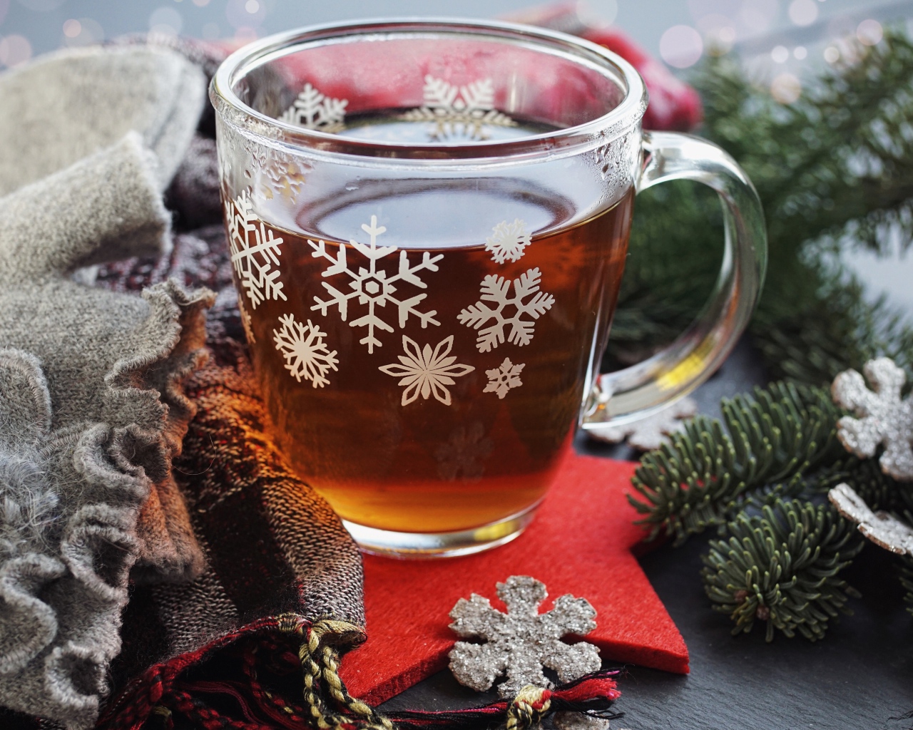 Стеклянная чашка чая на столе с ветками ели и шарфом 