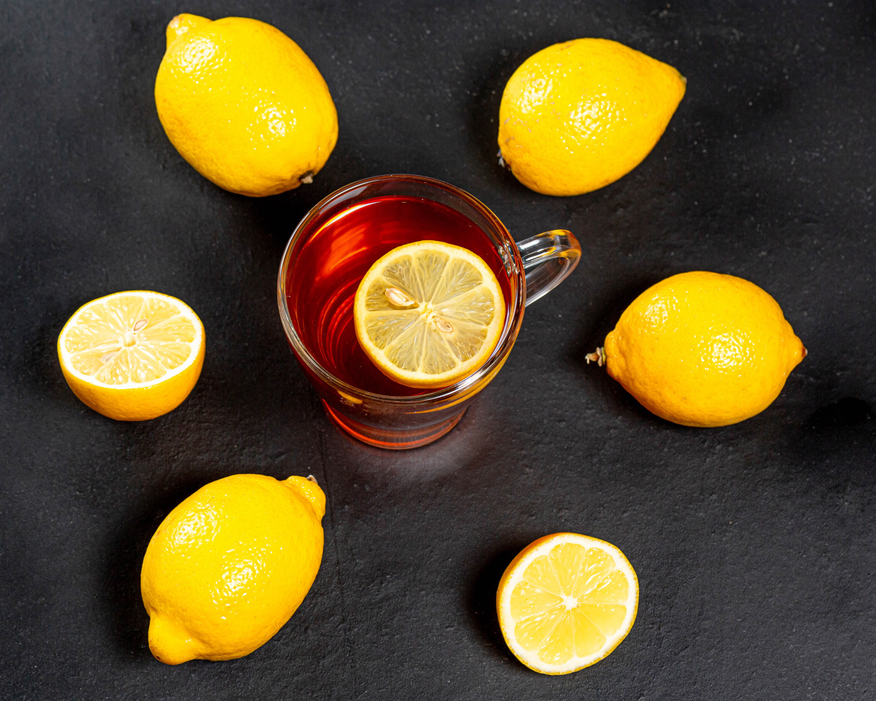 Стеклянная чашка чая с лимоном на сером столе 