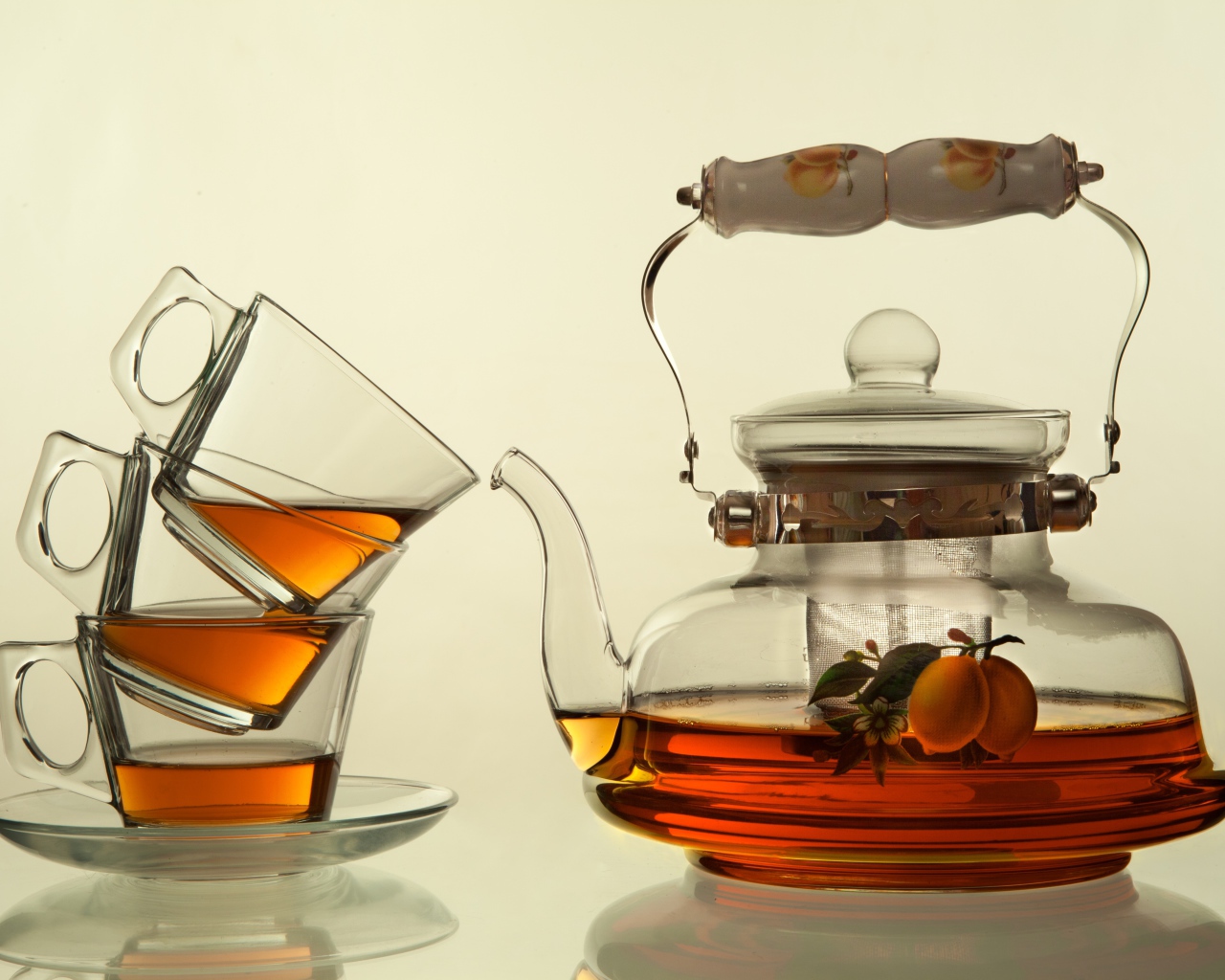Стеклянный чайник с чашками на белом фоне
