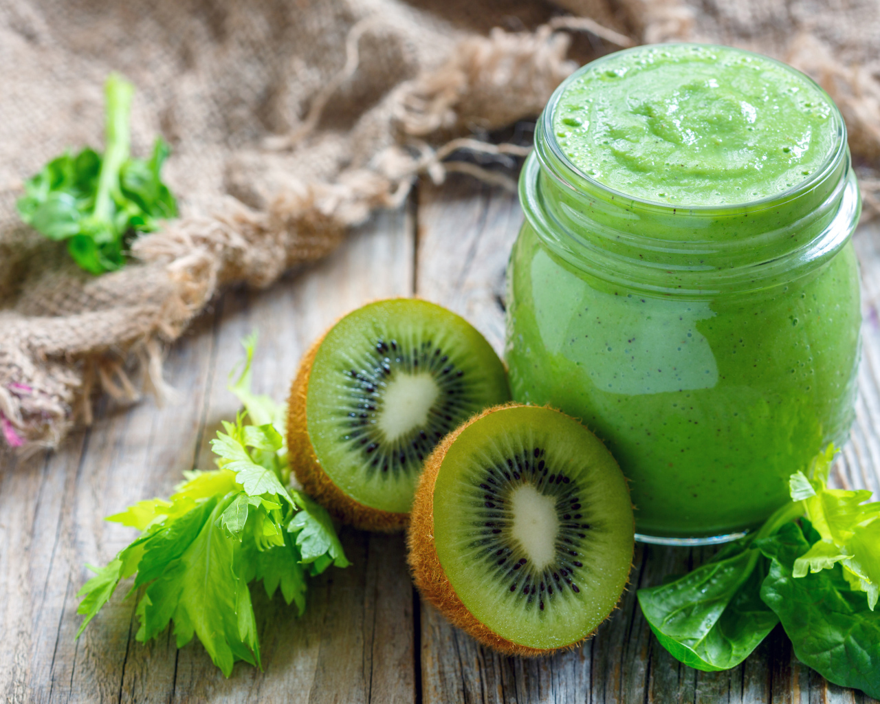 Зеленое смузи на столе с киви и зеленью 