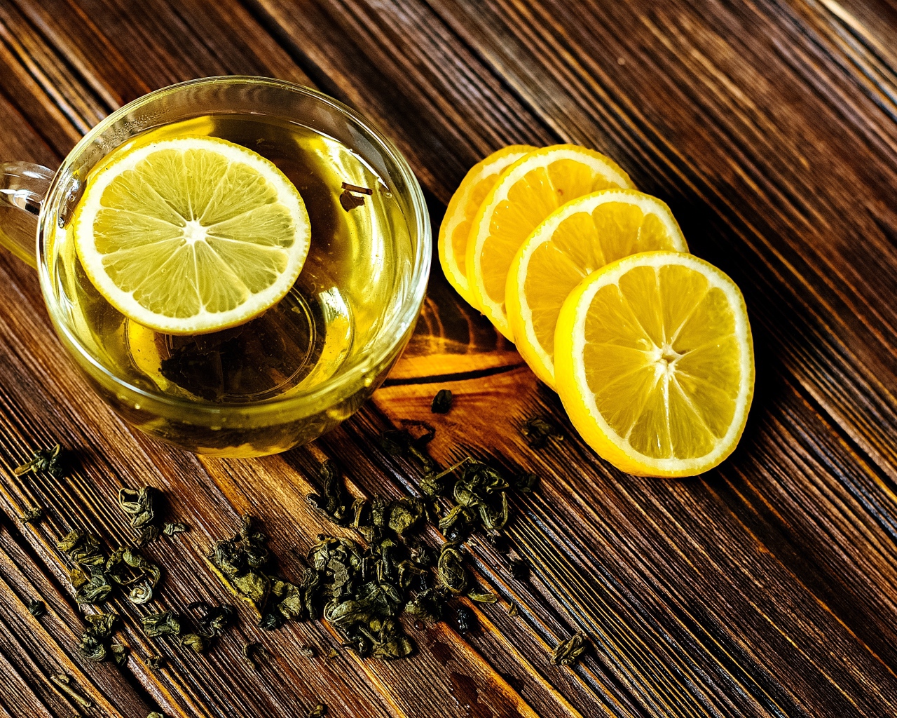 Зеленый чай в стеклянной чашке на столе с лимоном 