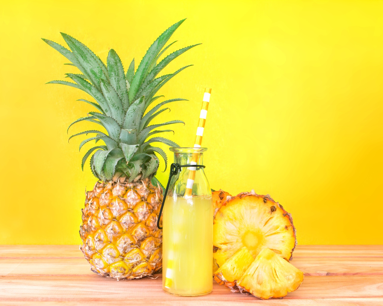 Сок в бутылке на столе с ананасами