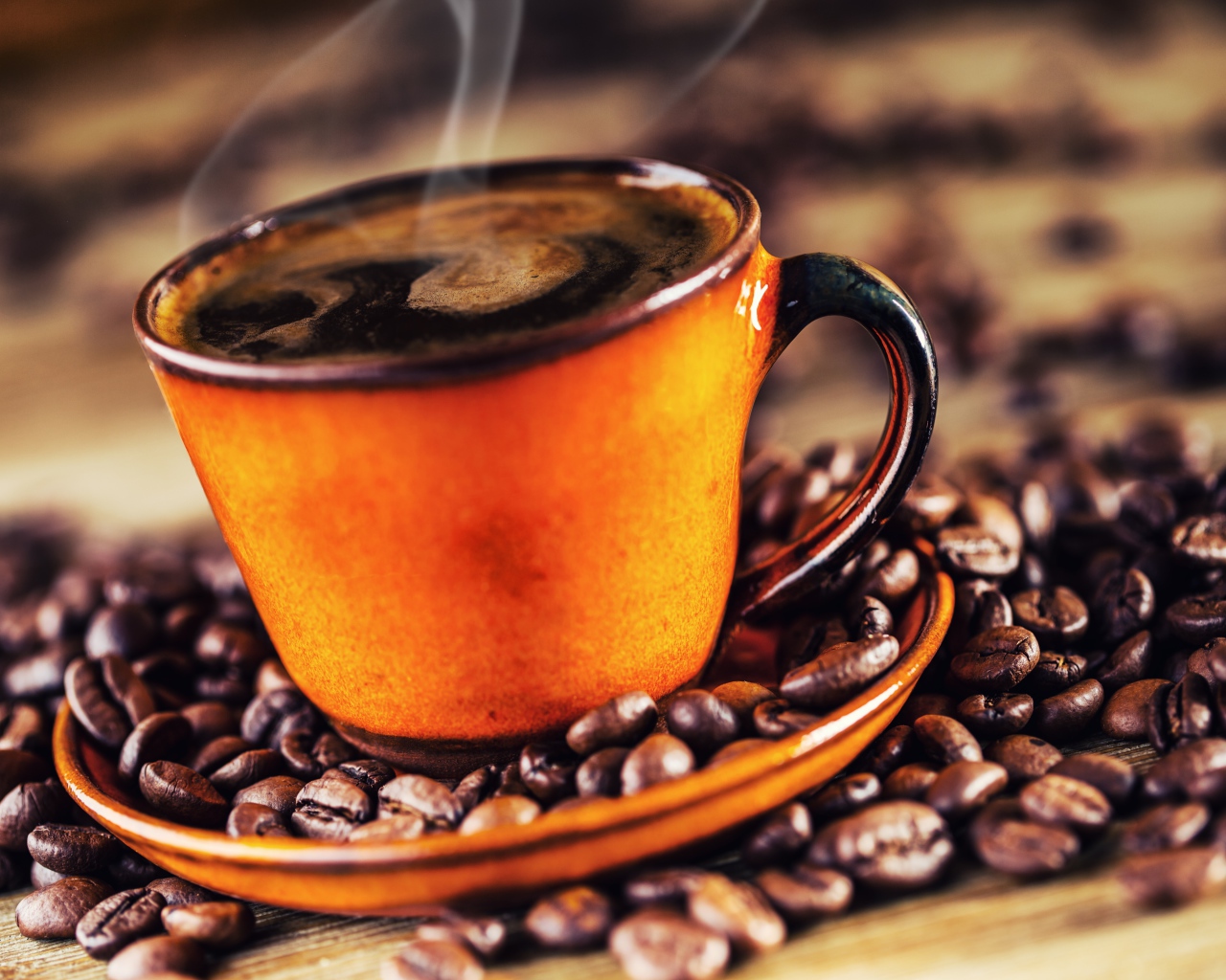 Оранжевая чашка горячего ароматного кофе на столе с зернами