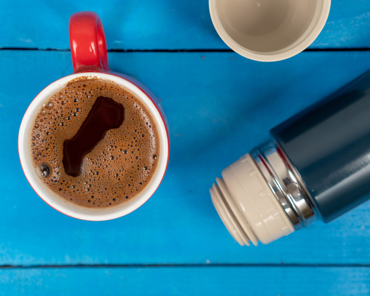 Красная чашка кофе с термосом на голубом столе 