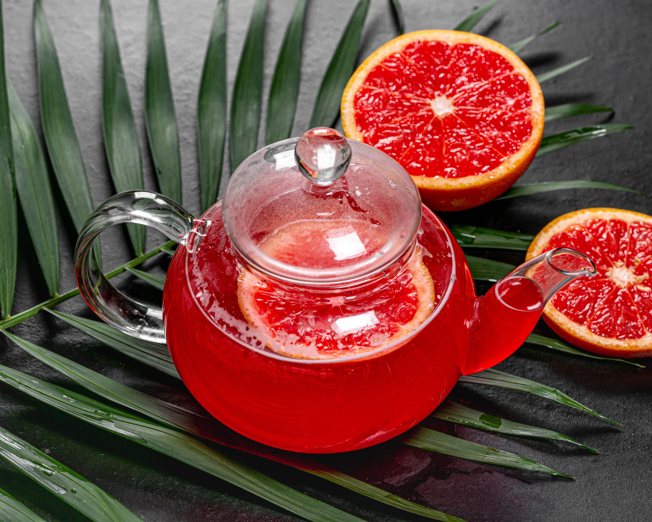 Красный чай в чайнике на столе в грейпфрутом и листьями