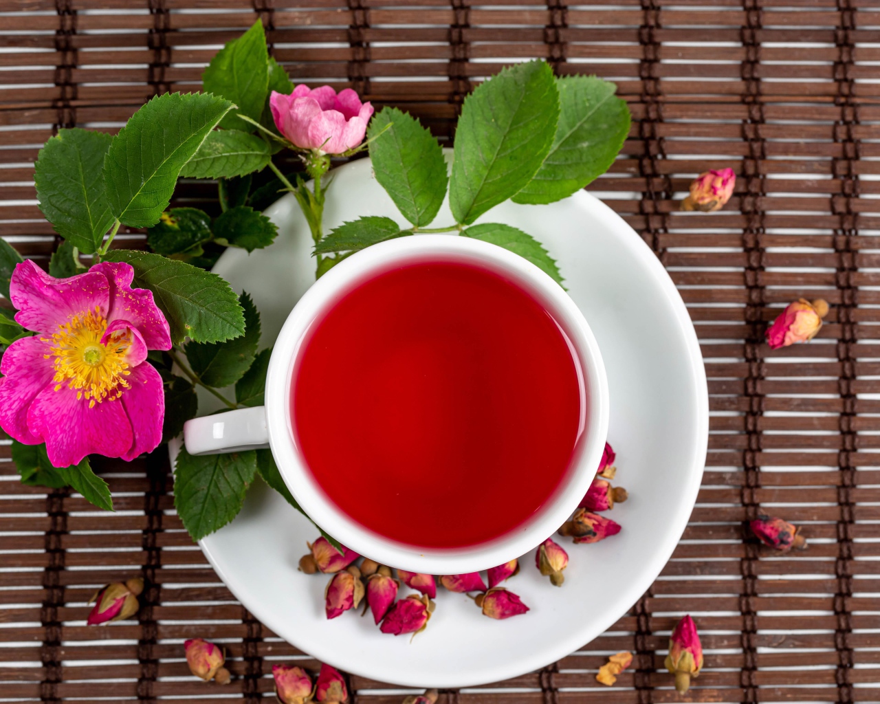 Красный чай с шиповника на столе с цветами