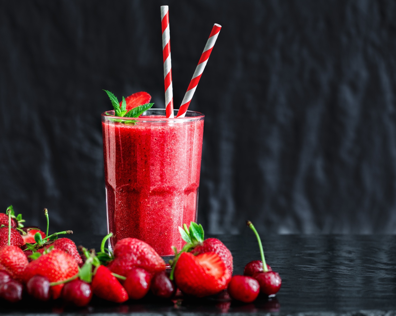 Смузи с ягодами клубники и вишни на столе