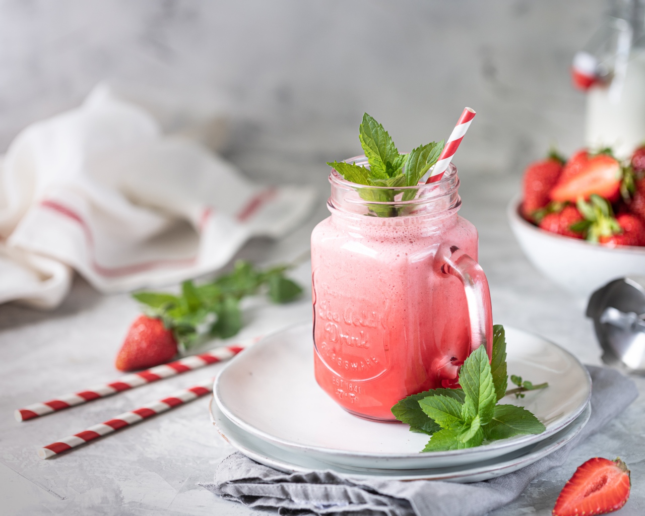Смузи с клубникой в банке с трубочкой и листьями мяты