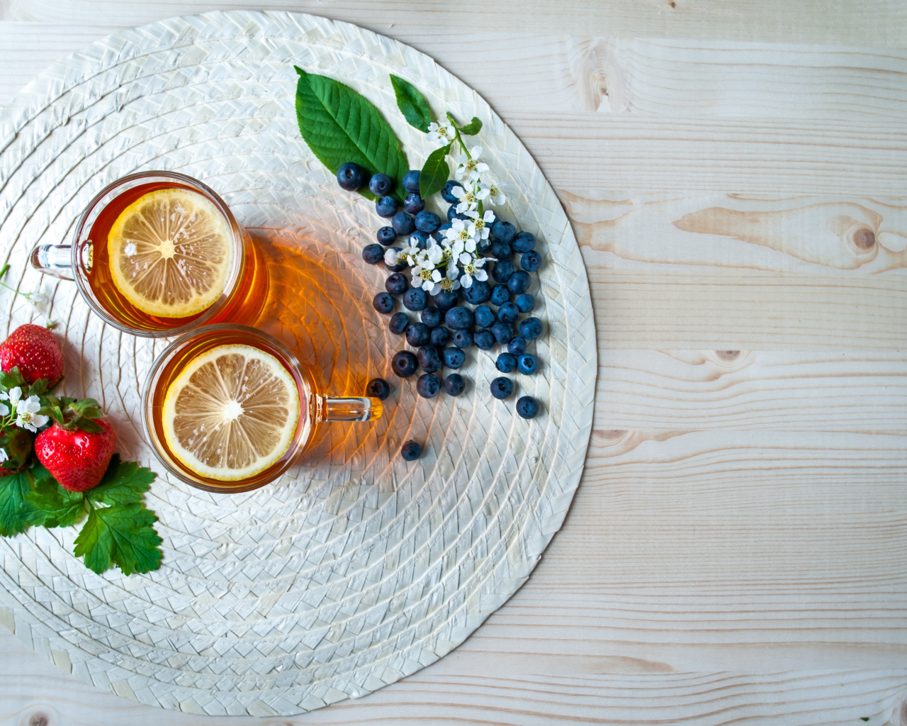 Чай с лимоном на столе с ягодами клубники и черники