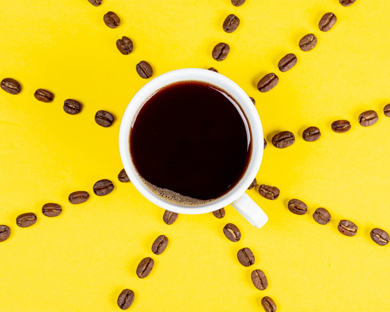 Солнце из чашки кофе с зернами на желтом фоне