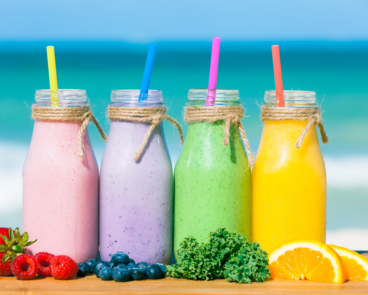 Три бутылочки со смузи на столе на пляже