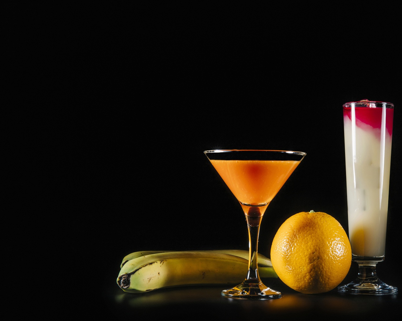 Два коктейля на черном фоне в бананом и апельсином