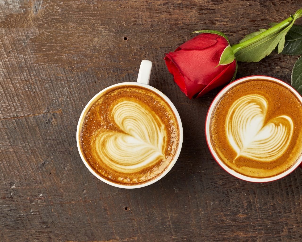 Две чашки капучино на столе с красной розой 