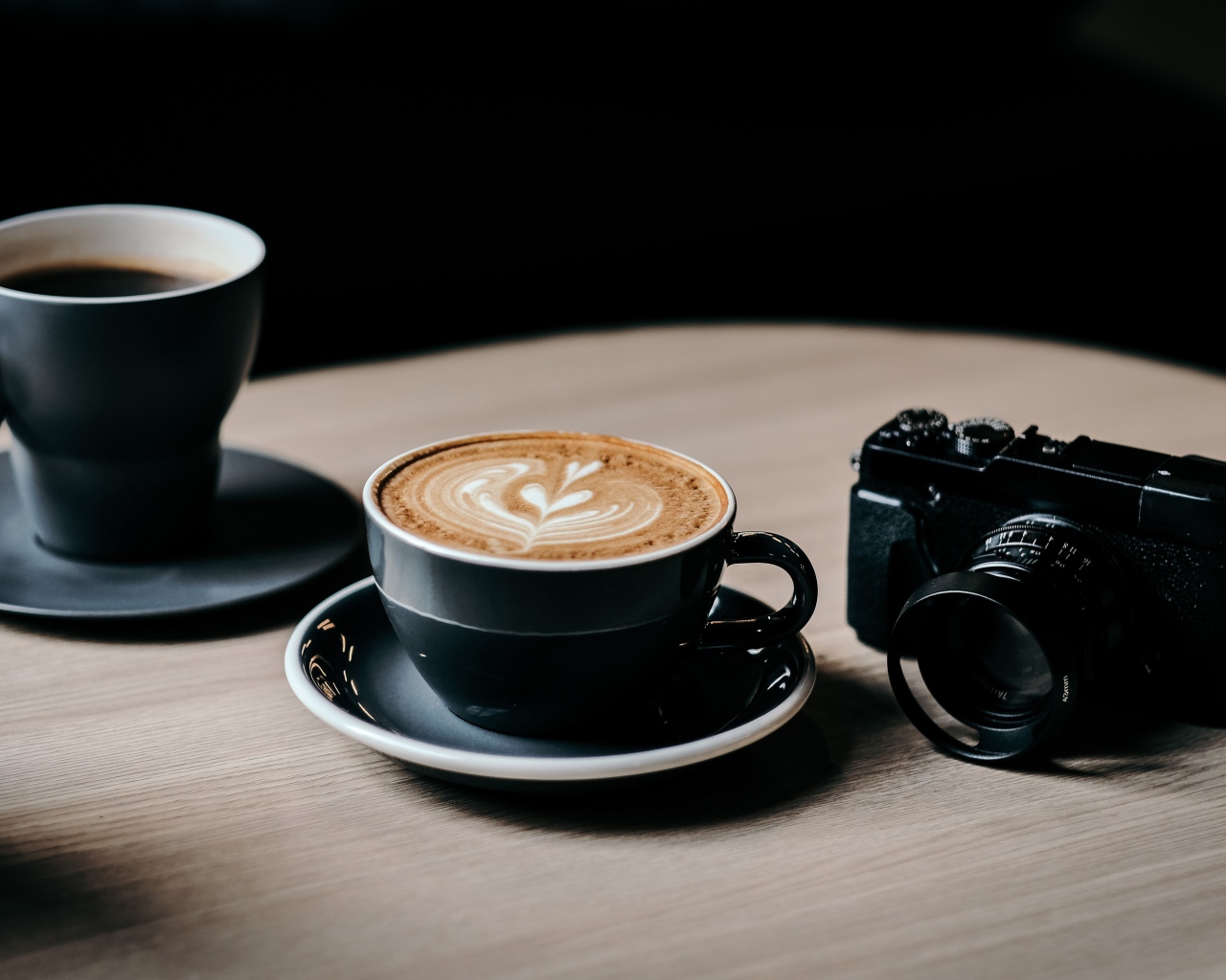 Две чашки кофе на столе с фотоаппаратом 