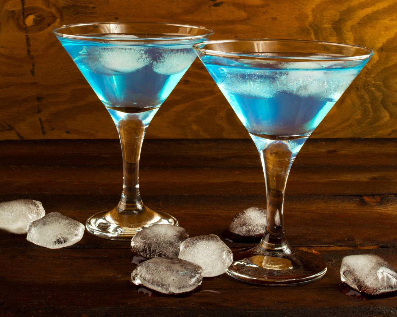 Два бокала коктейля на столе с кусочками льда