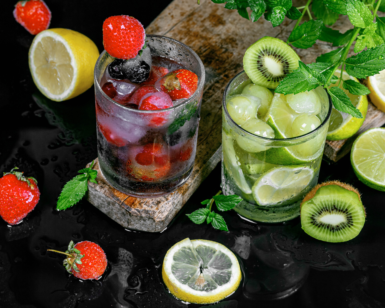 Два стакана мохито на столе с мятой, лимоном и клубникой 