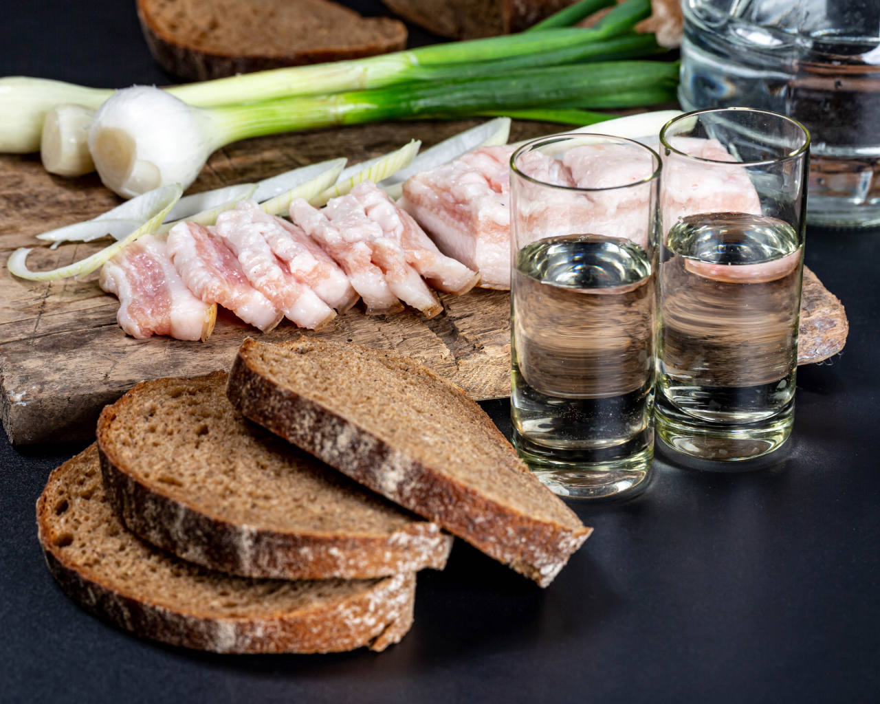 Две рюмки водки на столе с аппетитной закуской 