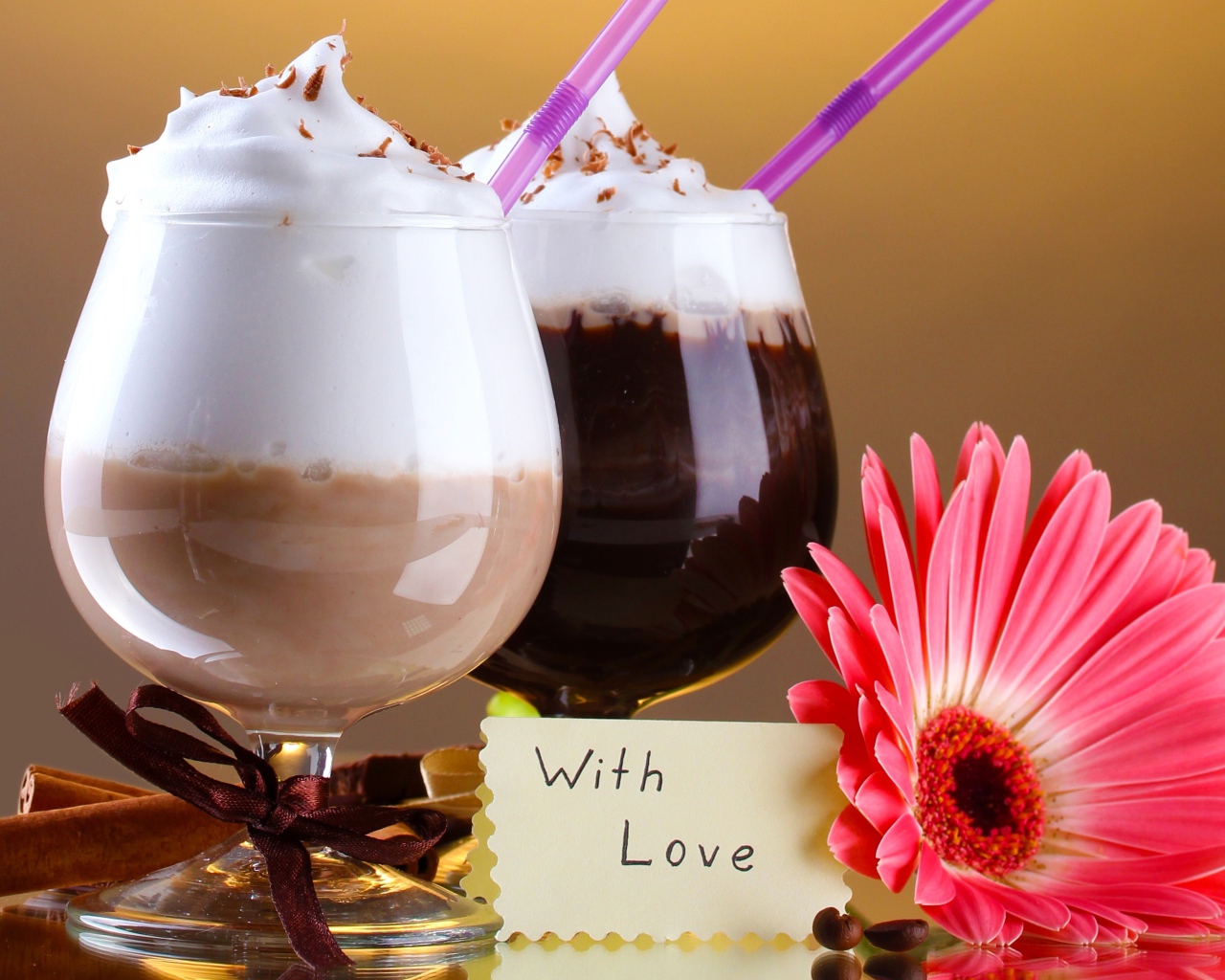 Два бокала с напитком на столе с розовой герберой