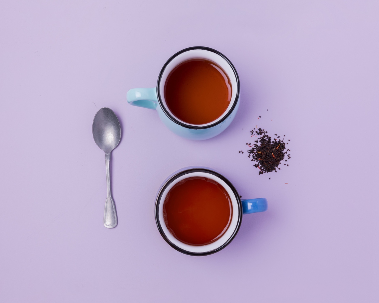 Две железные чашки чая на сиреневом фоне с ложкой