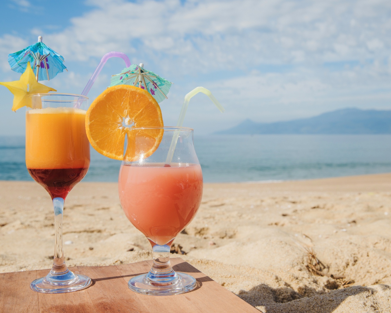 Два тропических коктейля на пляже в лучах солнца