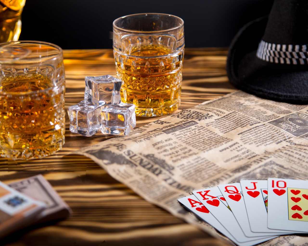 Виски со льдом на столе с картами, газетой и шляпой