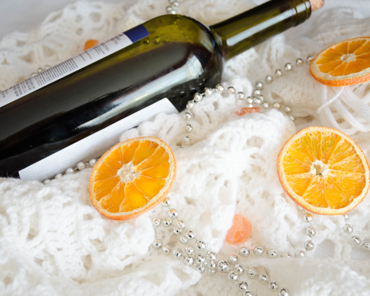 Бутылка вина и кусочки апельсина на белом платке 