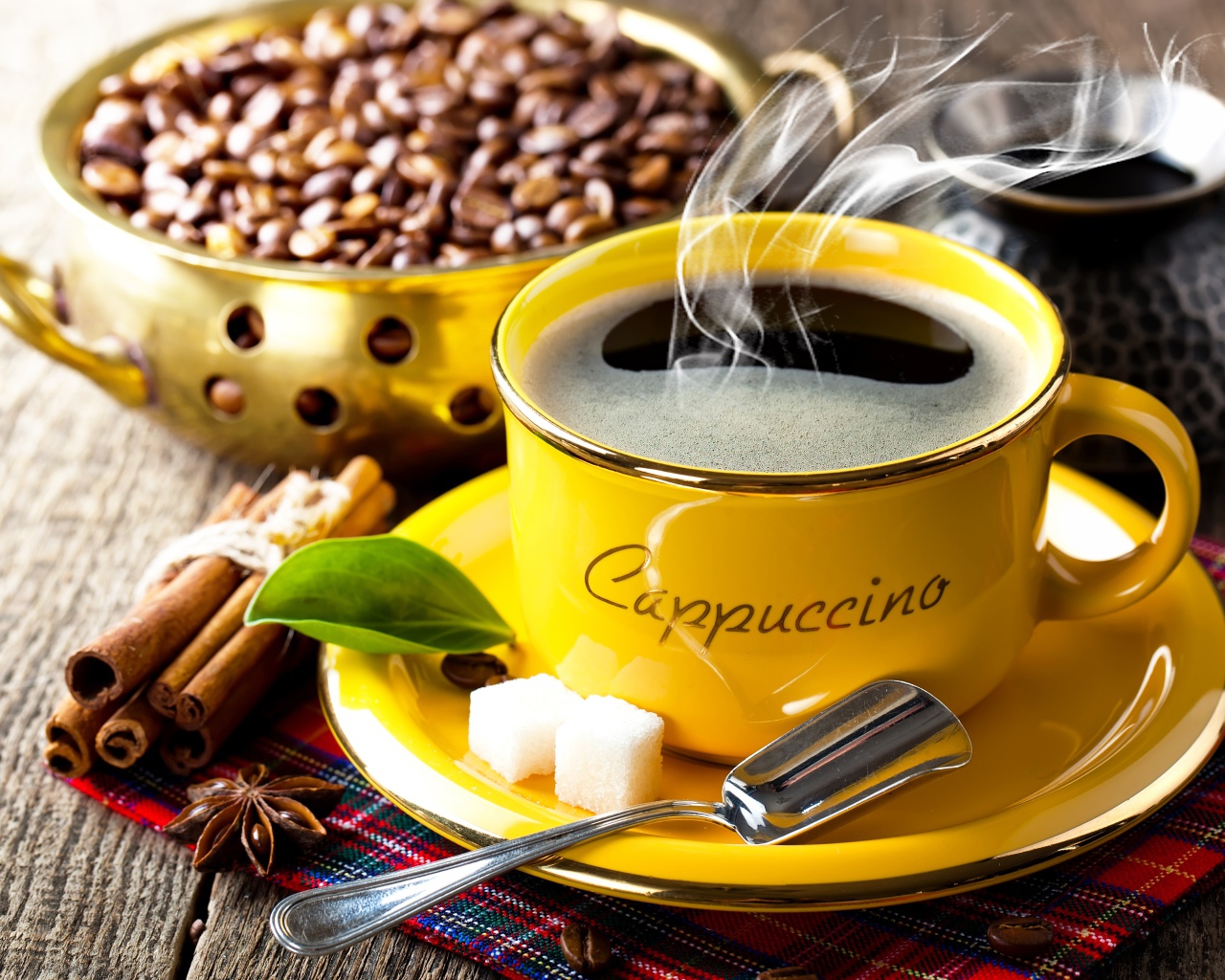 Желтая чашка с горячим кофе на столе с зернами и корицей 