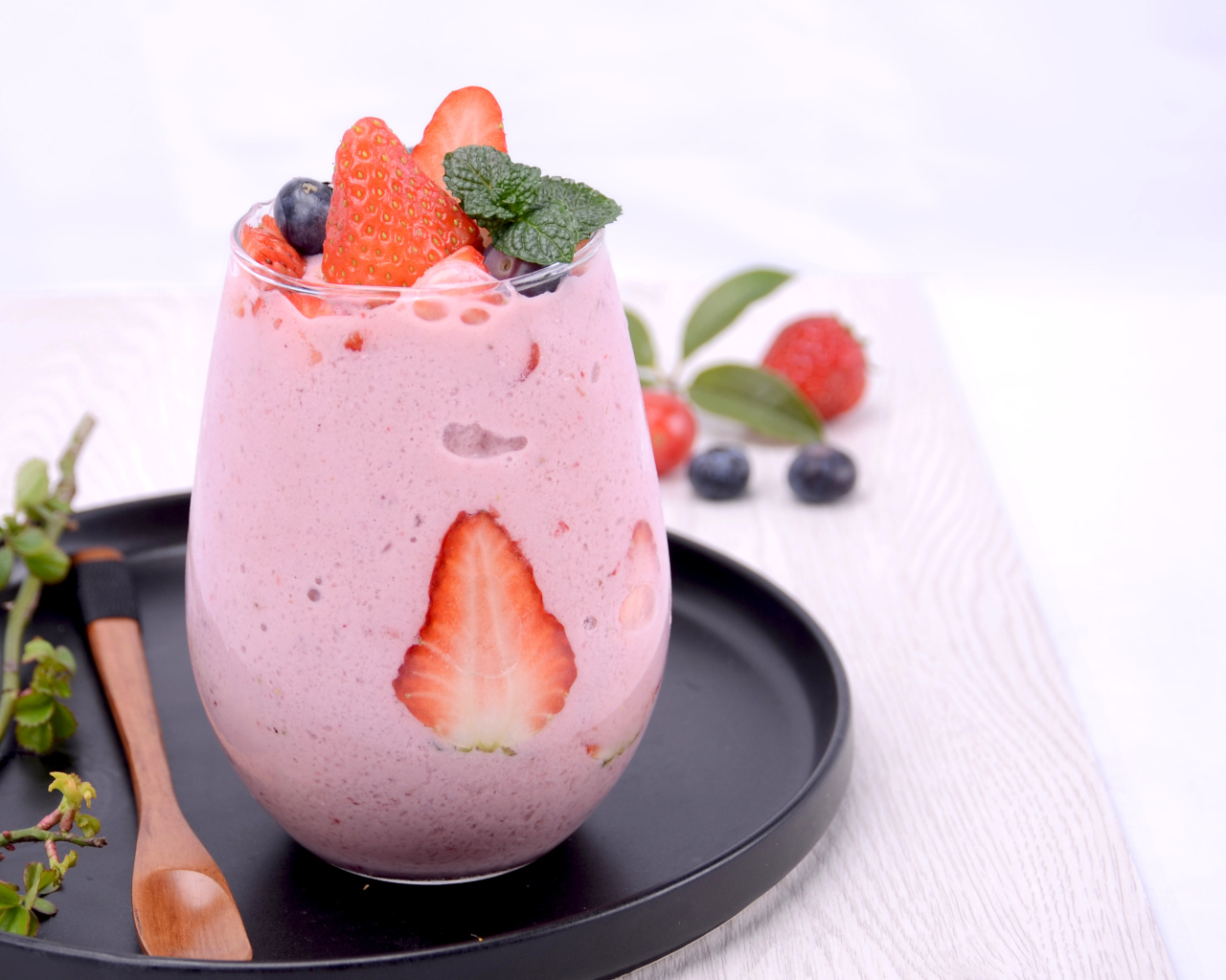 Йогурт в стакане с ягодами черники и клубники