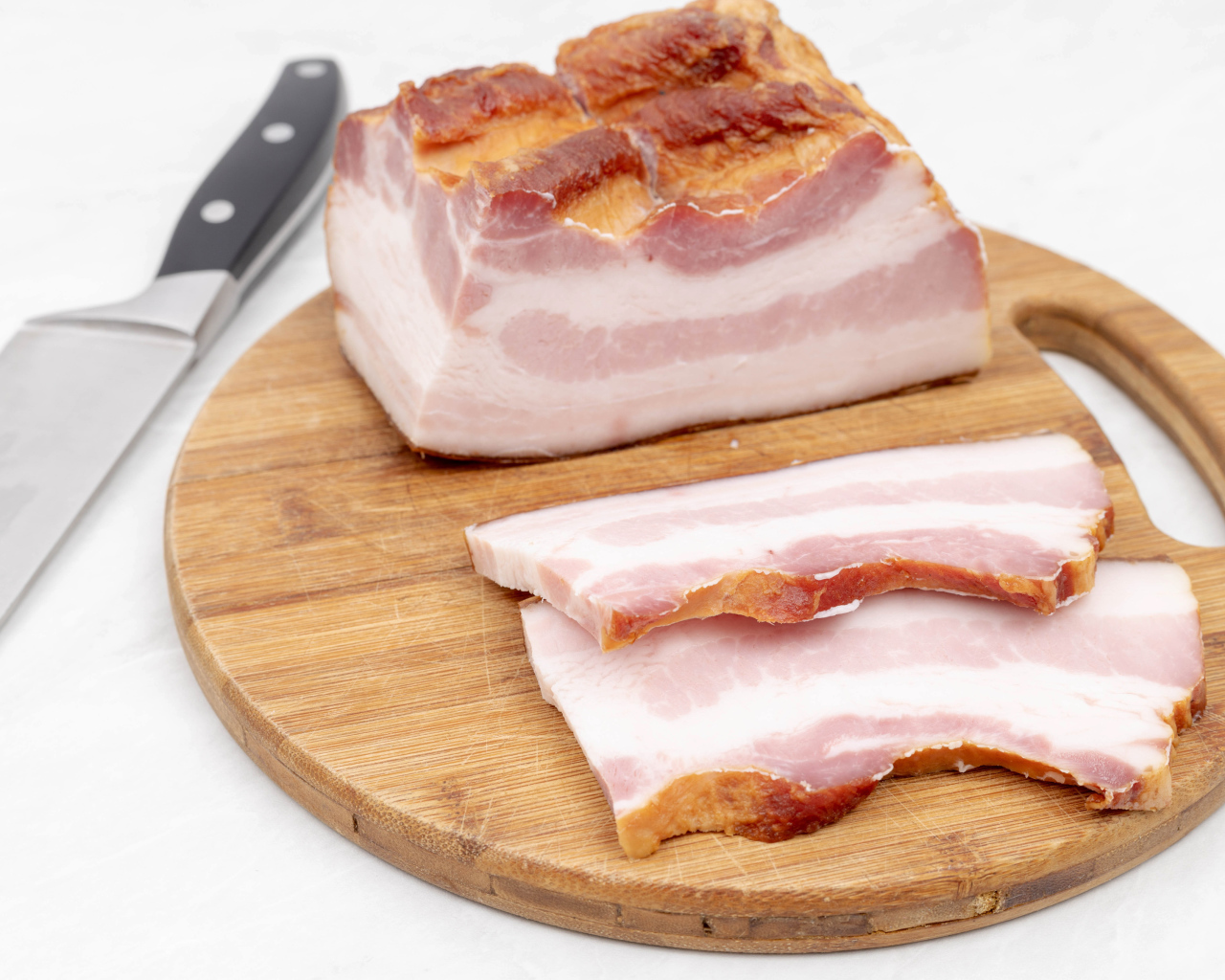 Кусок вкусного копченого сала на доске с ножом