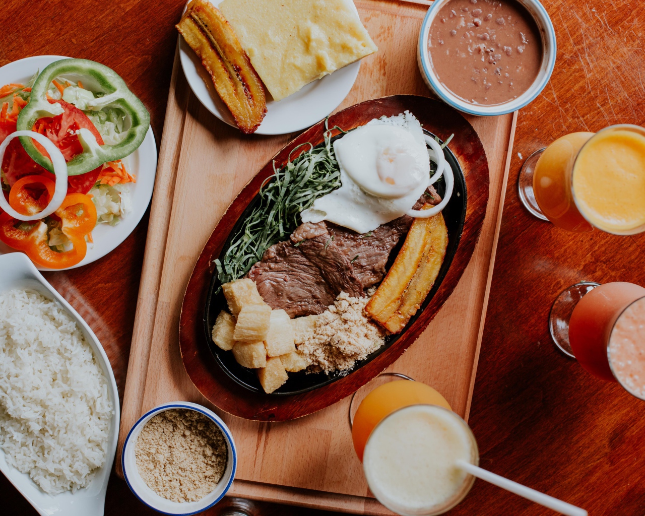 Кусок мяса в жаровне на столе с напитками, овощами и рисом