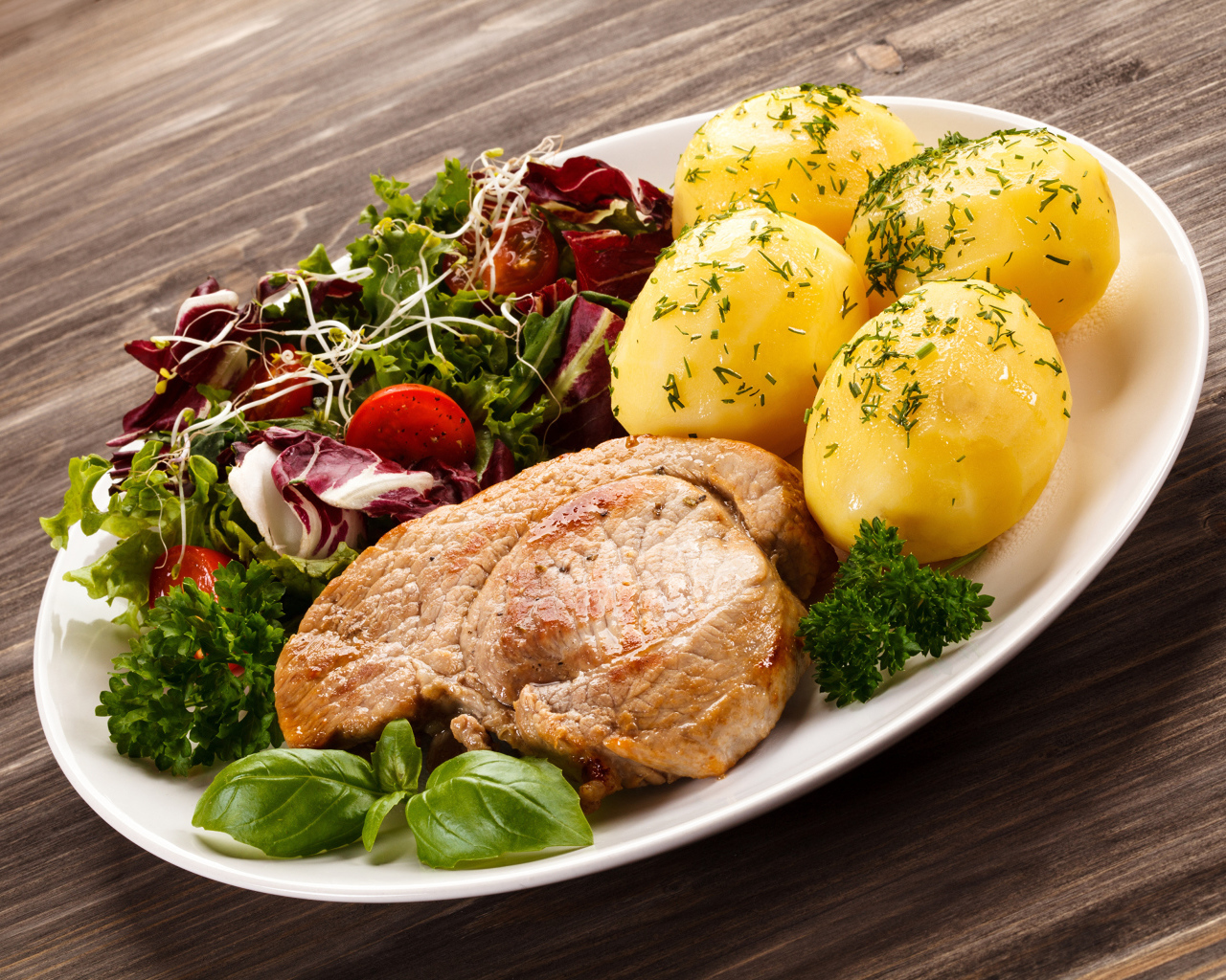 Кусок мяса на тарелке с картофелем и салатом