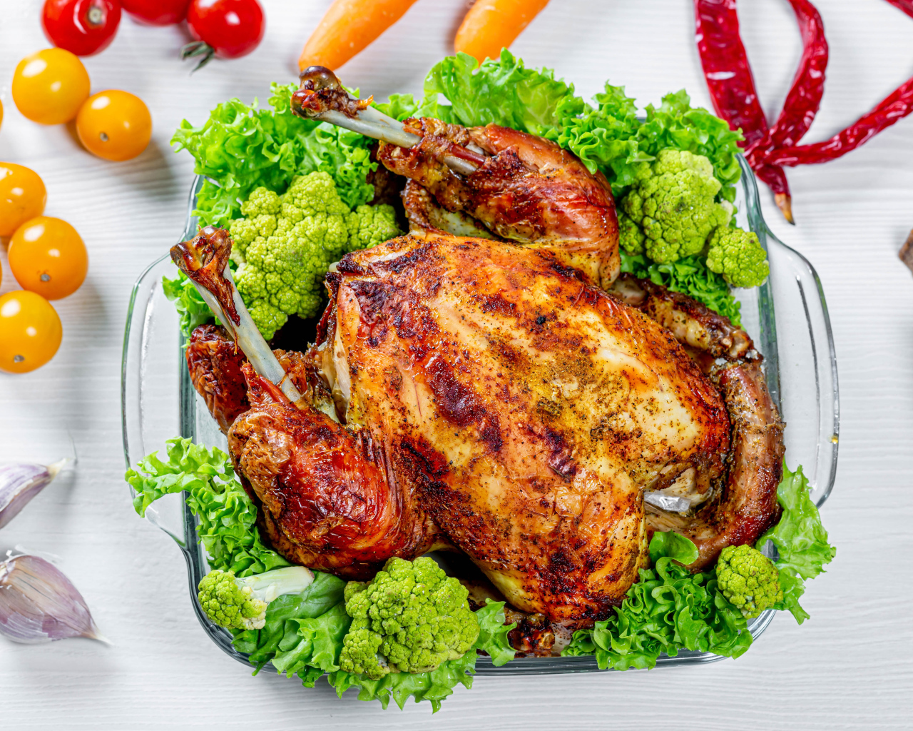 Запеченная курица с брокколи и листьями салата на столе с овощами